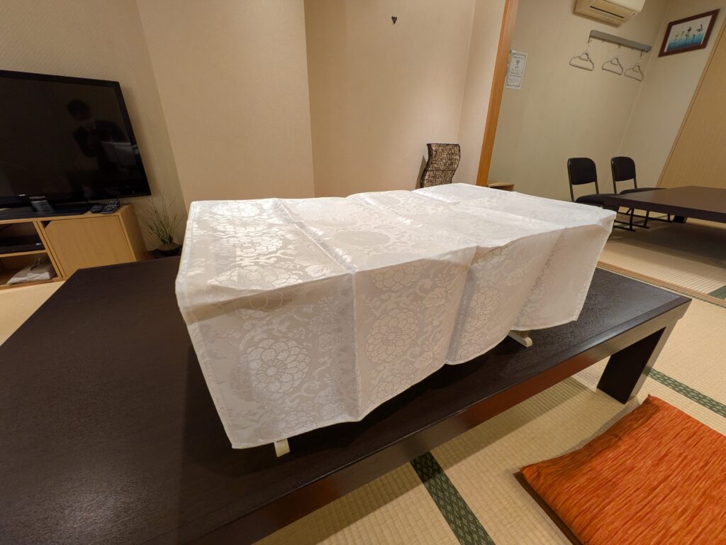 堺市の家族葬で使う後飾り祭壇の説明用に、経机と白い内敷だけを整えたシンプルな設置例が写っている。