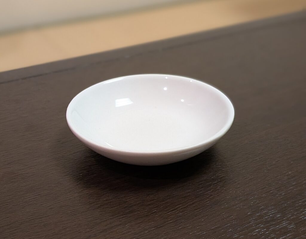 堺市の家族葬で後飾り祭壇に用いる白い仏飯器が写っており、白米を供えるための落ち着いた陶器の供物具がわかる写真です。