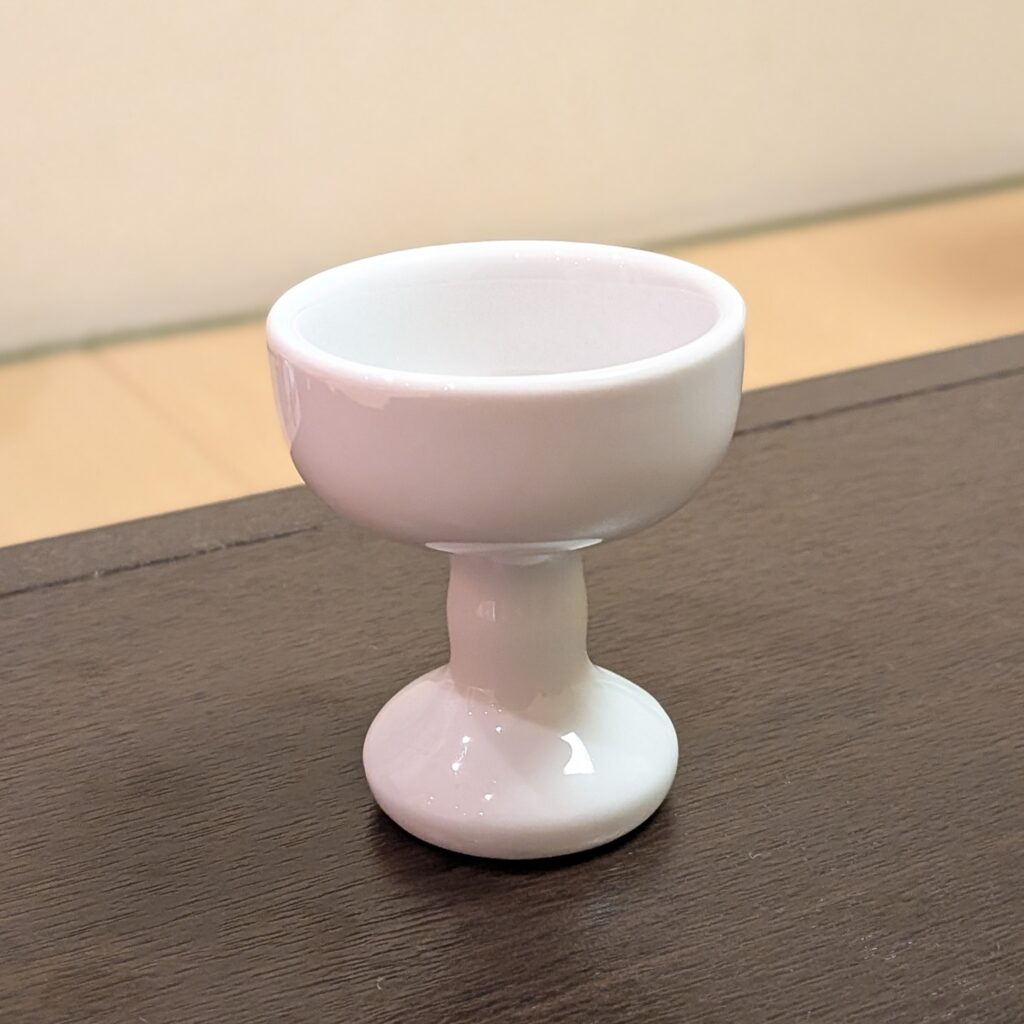 堺市の家族葬で後飾り祭壇に用いる白い仏飯器が写っており、白米を供えるための落ち着いた陶器の供物具がわかる写真です。