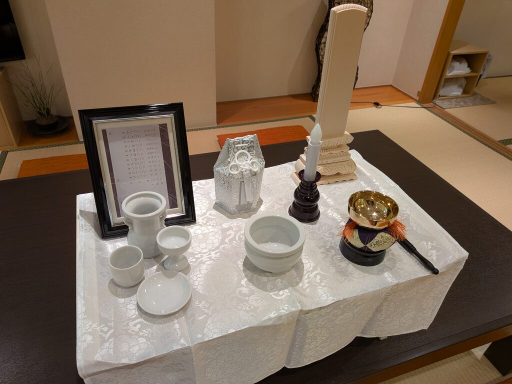 堺市の家族葬で使用される後飾り祭壇が写り、白木位牌や陶器の供物具、遺影写真など中陰壇の基本的な配置が整っている様子。