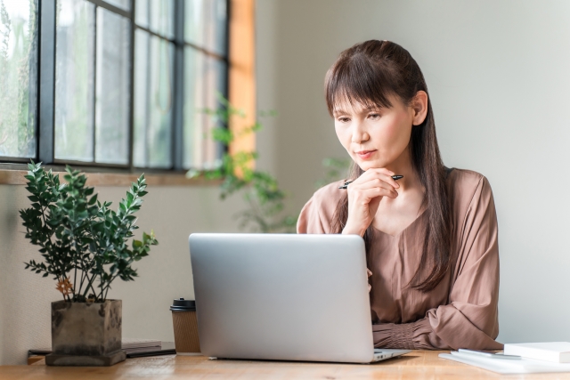 堺市で葬儀や家族葬を検討し、ノートパソコンの前で内容に悩みながら情報を調べる中年女性の様子。