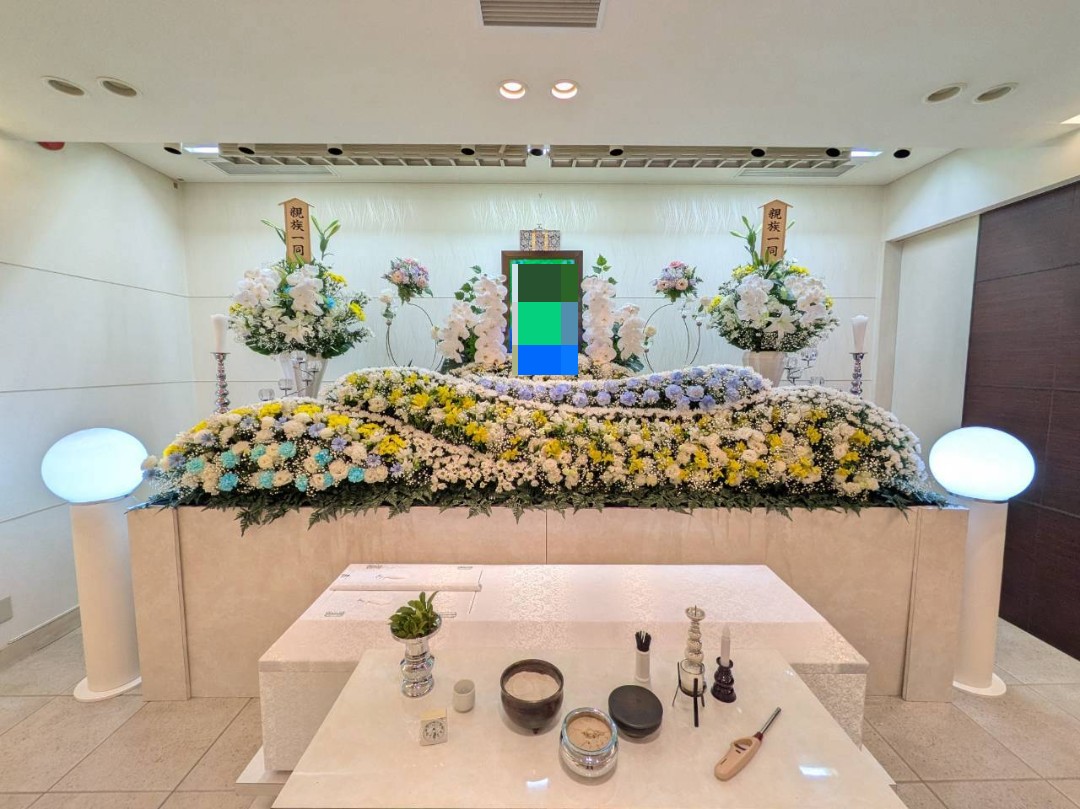 堺市の家族葬ホールで執り行われた一日葬の花祭壇。白と黄色を基調とした温かみのある祭壇の様子です。